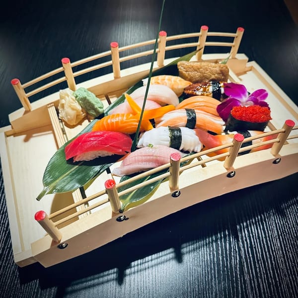 Assorted Kanpai Sushi nigiri and sashimi artfully arranged on a wooden boat platter.