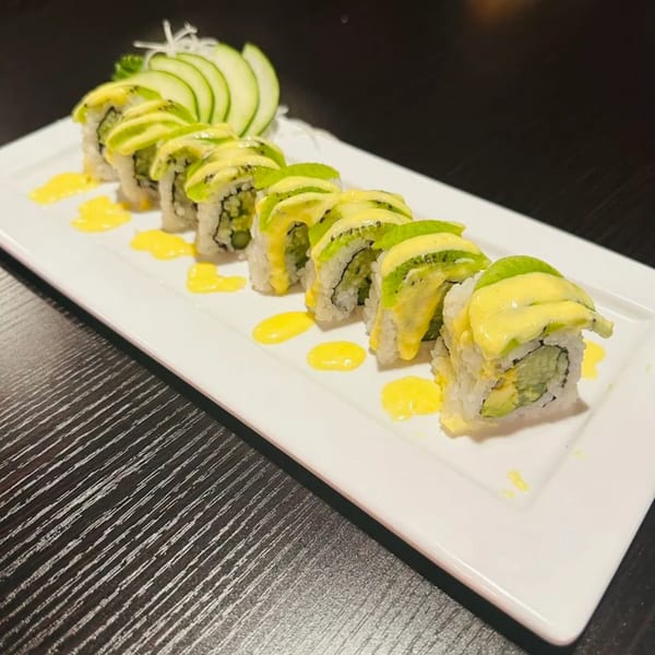Kanpai Sushi's sushi rolls topped with kiwi and yellow sauce, garnished with cucumber slices.