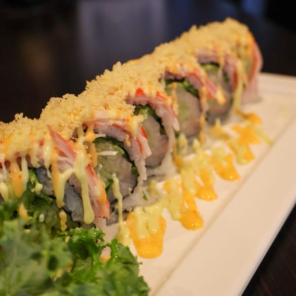 Kanpai Sushi's crispy sushi roll with crab, avocado, and sauce, served on a white plate.