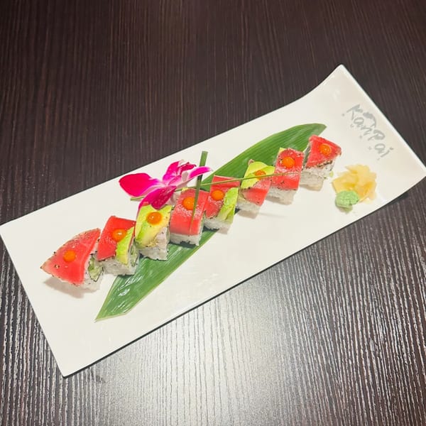 Kanpai Sushi's tuna and avocado sushi roll, garnished with a pink orchid and served with ginger and wasabi.